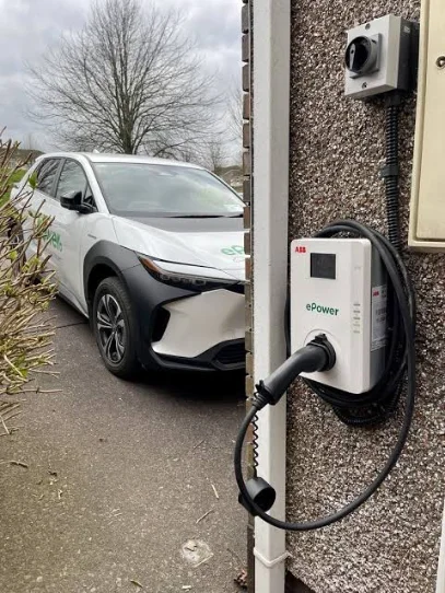 Electric car charging on a driveway from a wall-mounted unit